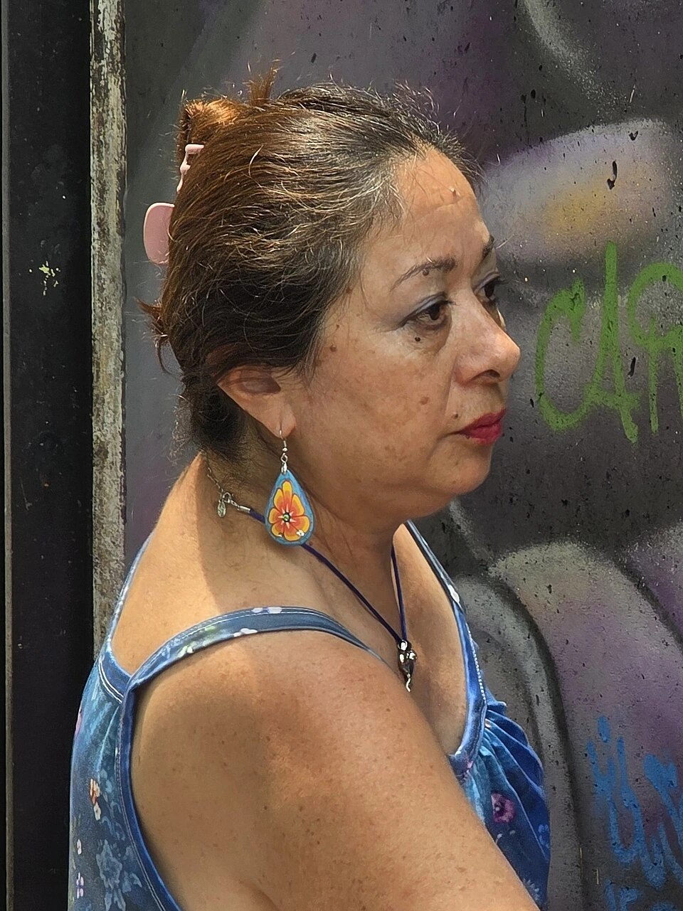 Lady Pink, the graffiti artist Sandra Fabara, standing in front of a graffiti-covered wall.