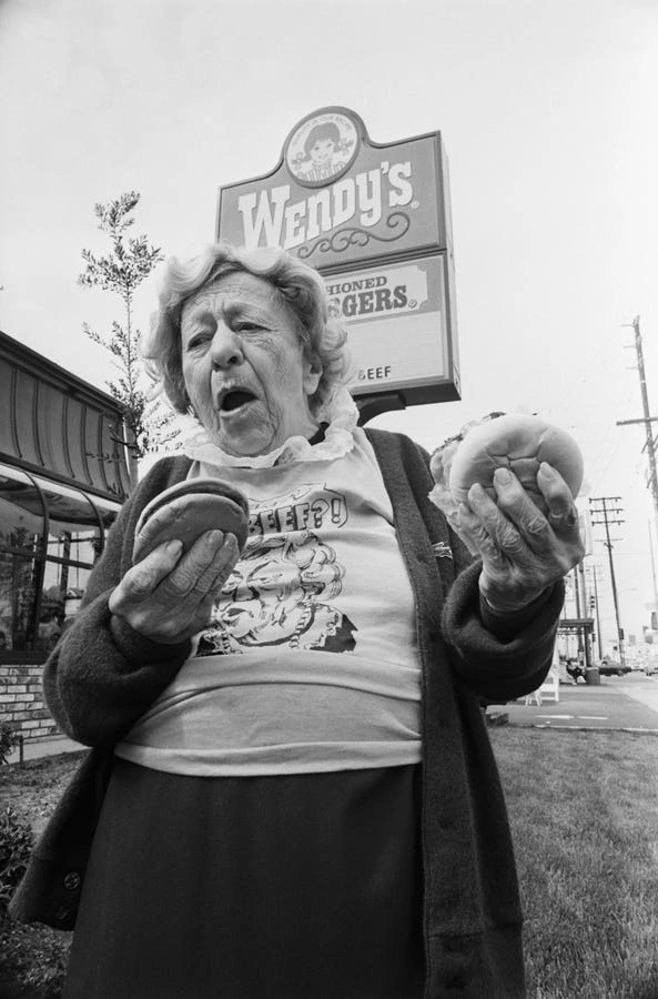 Clara Peller holding hamburgers in front of a Wendy’s sign