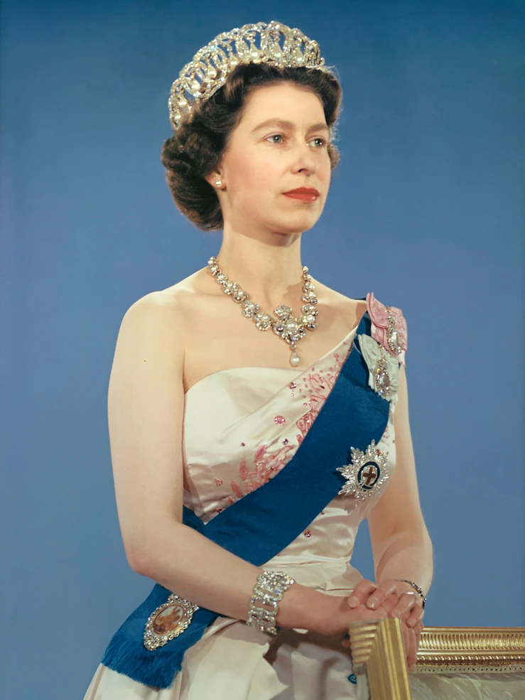 Queen Elizabeth II in an official portrait wearing a tiara and ceremonial dress against a blue background.